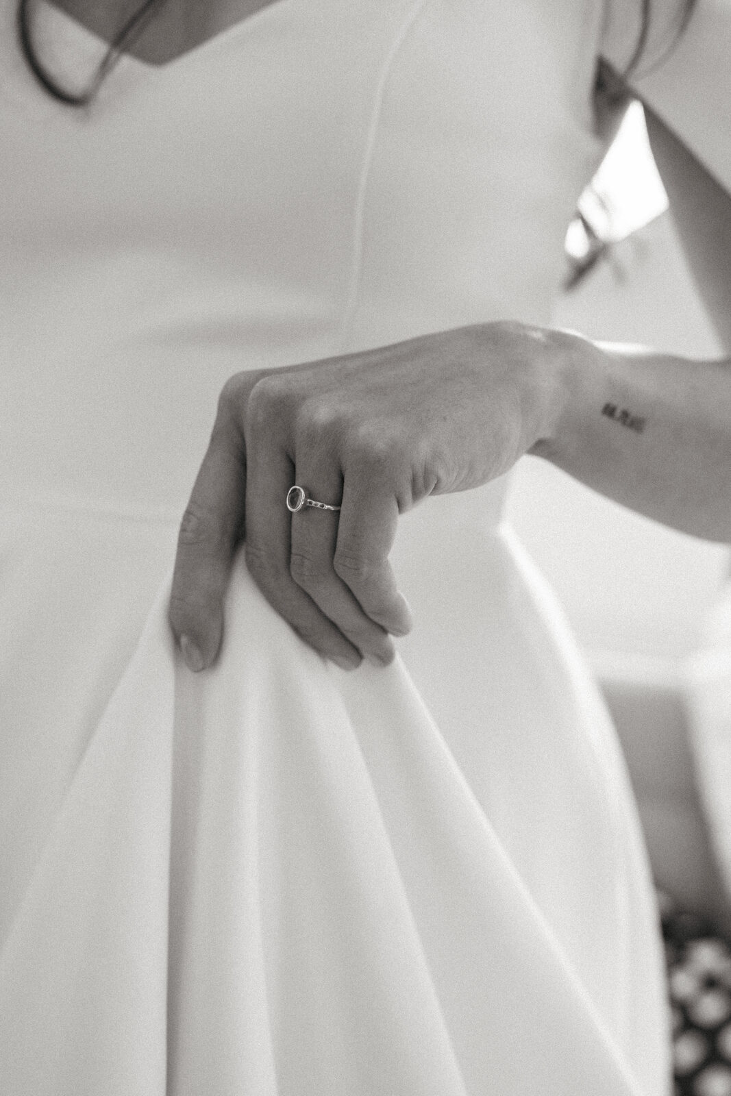 Close-up of a hand resting on a silk wedding dress