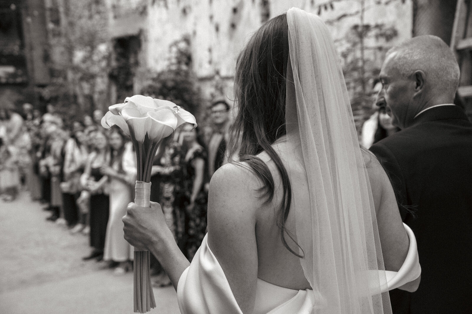 Bride from behind holding a bouquet during the ceremony
