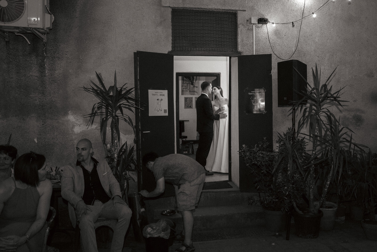 Bride and groom standing in a lit doorway at night